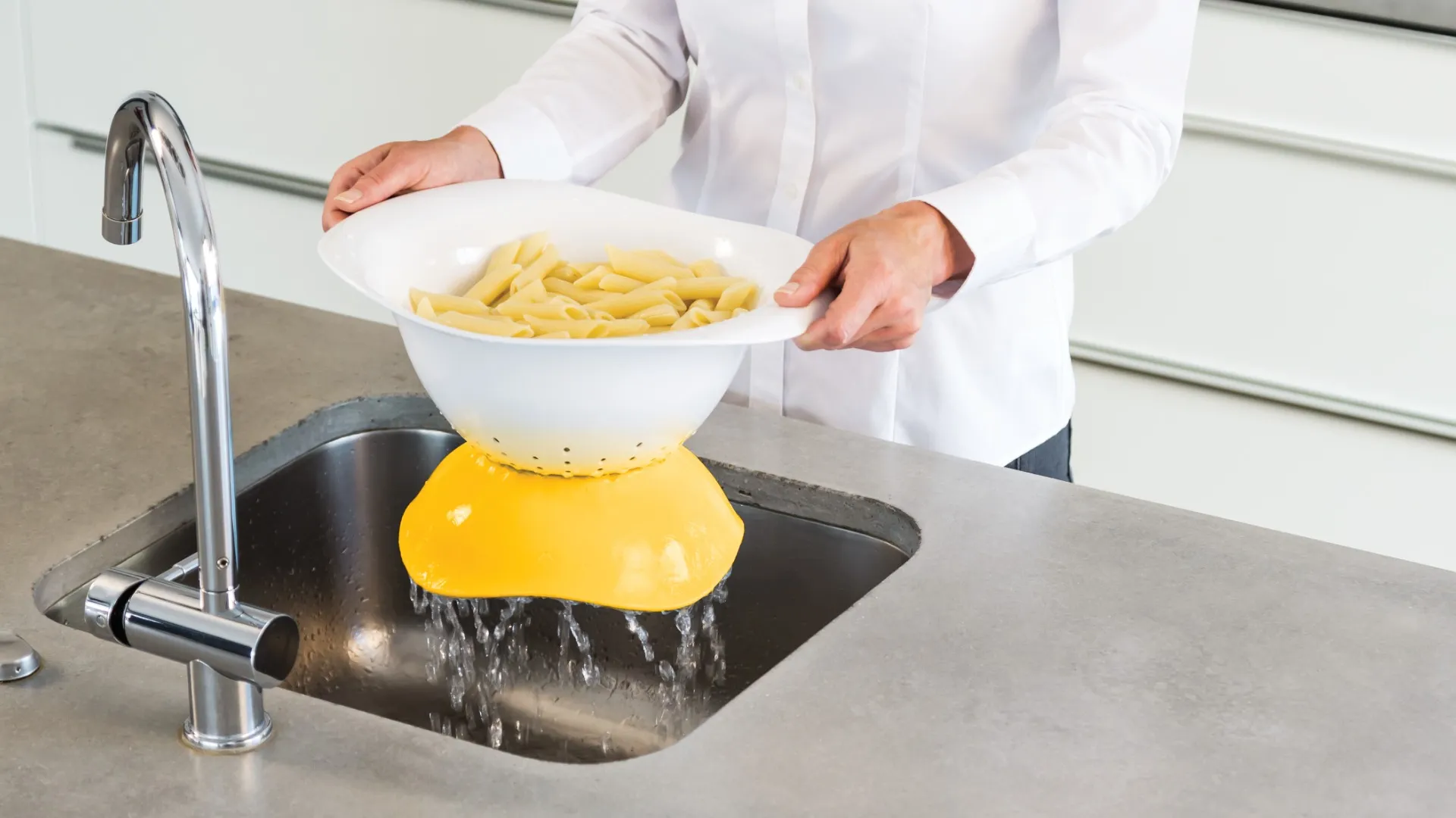 Draining pasta through the Colandish colander into a kitchen sink