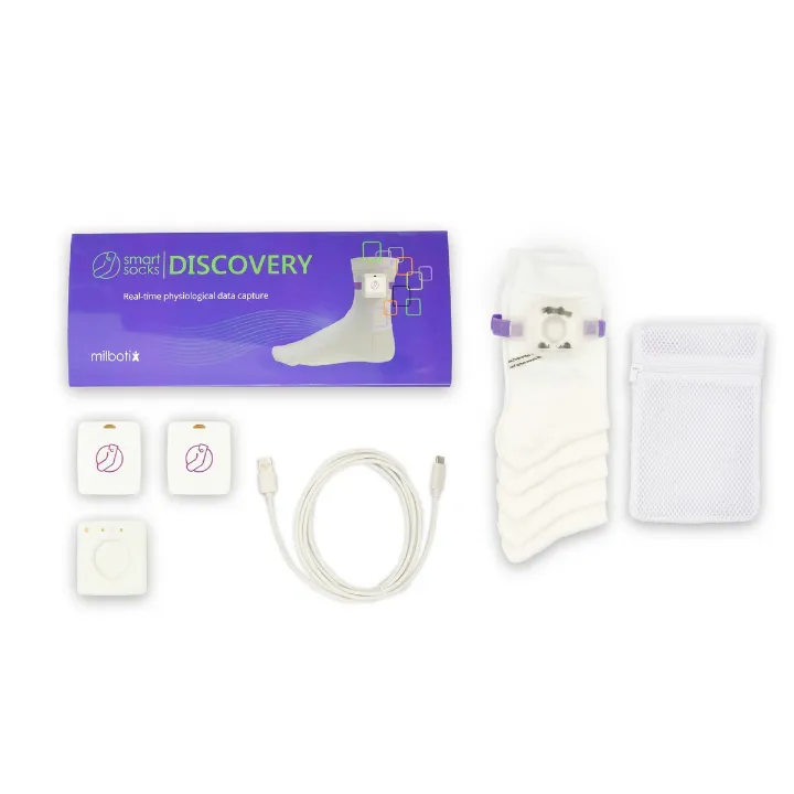 The Milbotix SmartSocks Discovery kit laid out flat: the purple retail box, three white sensor modules, a white charging cable, a stack of white socks with a sensor clipped to the top pair, and a mesh laundry bag.