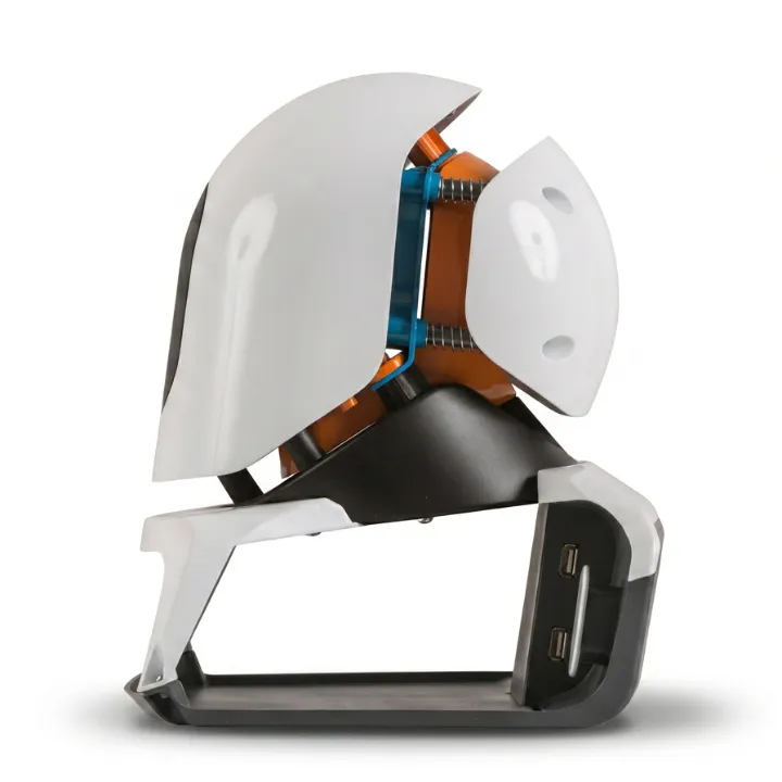 The Voya headset stand seen side on, its white outer shells opened around the orange inner cradle and blue clip, seated on a black moulded base with two USB ports.